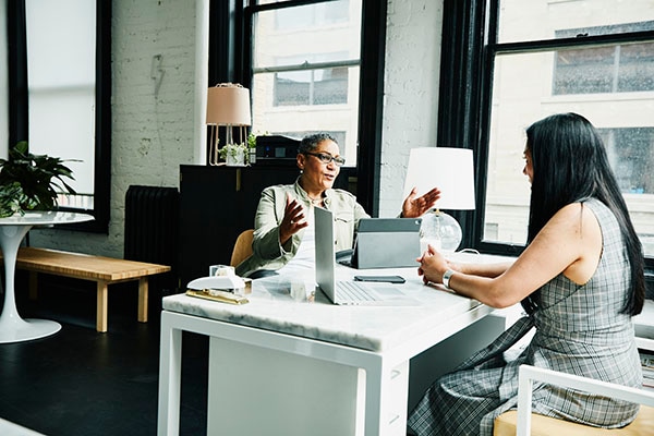 Female financial advisor in discussion with a woman at her desk in an office