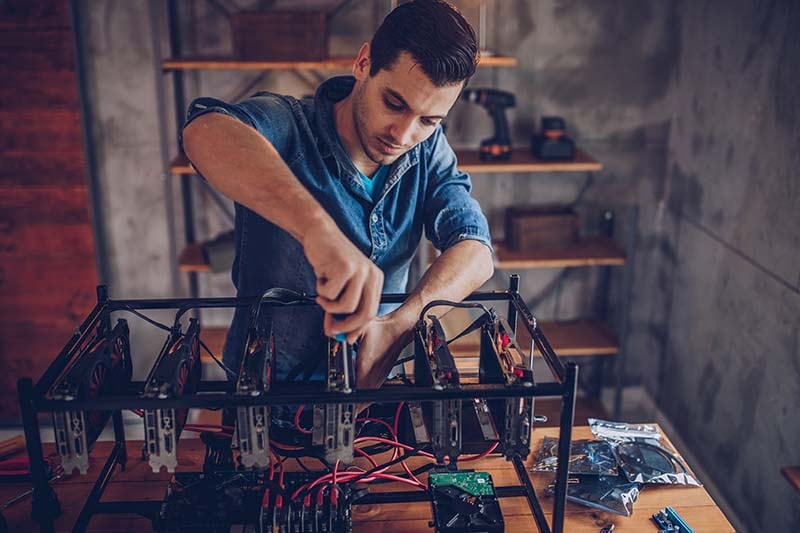 Adult man in denim shirt works on electronics at a wooden table