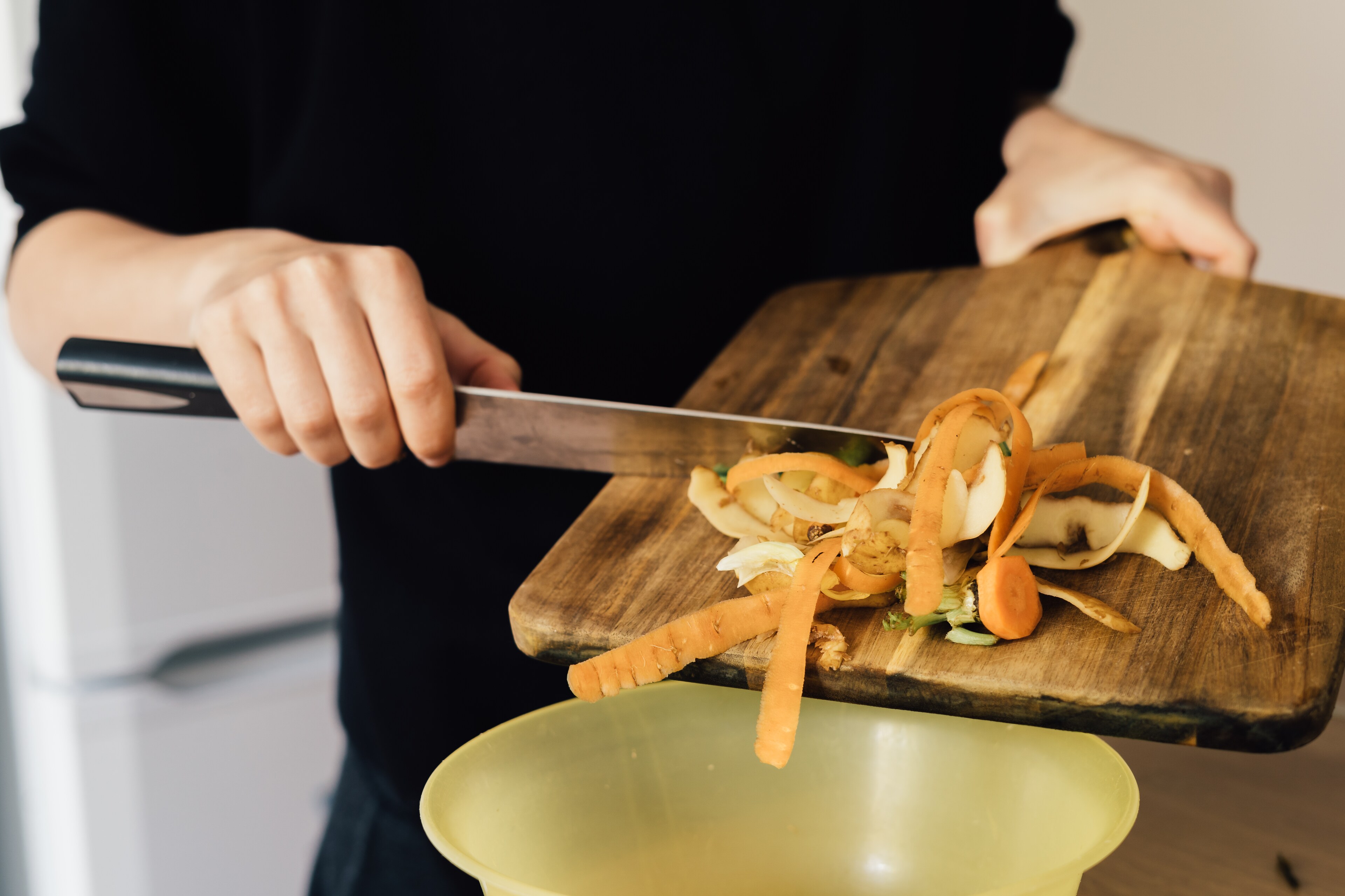 A man drops food scraps into a composting container