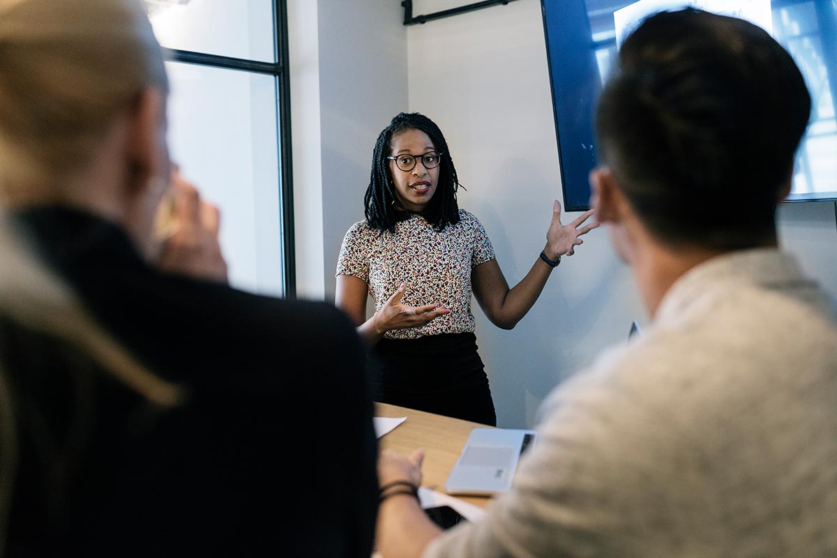 A woman presents to coworkers during a meeting