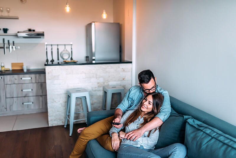 a man and a woman sit together on a couch in their new living room