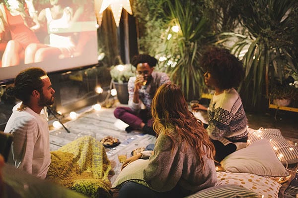 Group of friends watching TV together in backyard
