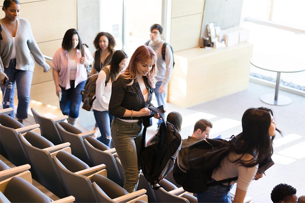 A group of students entering a lecture hall and taking their seats.