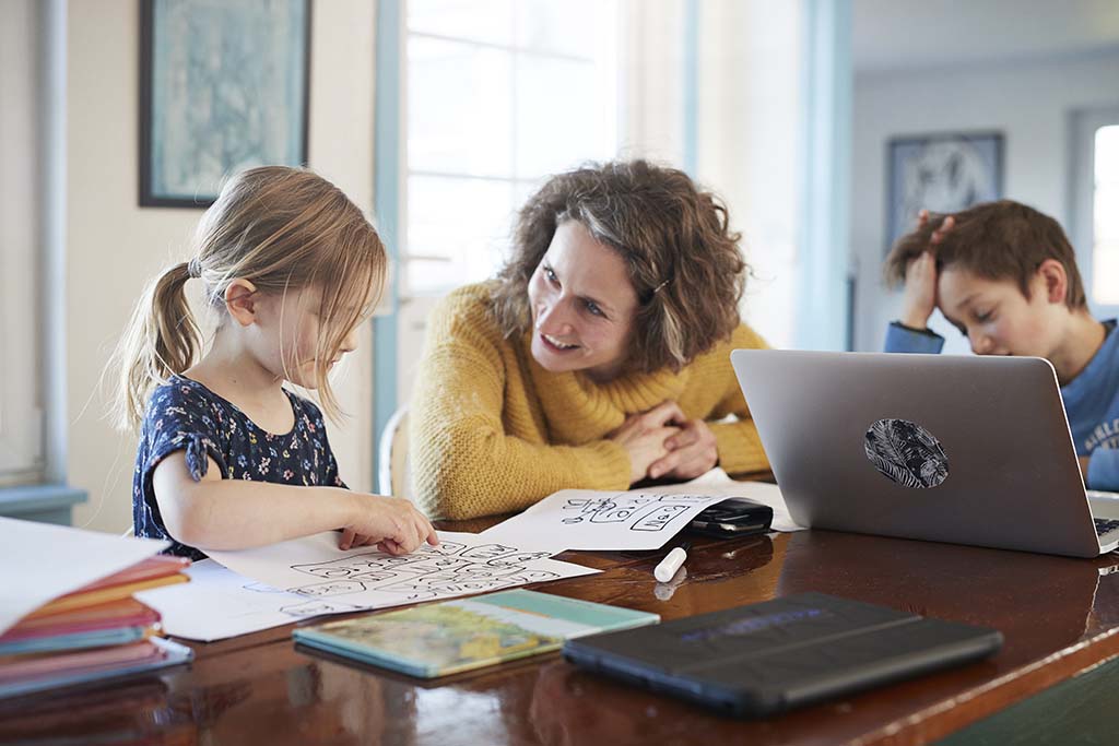 Mother homeschooling daughter and son at table