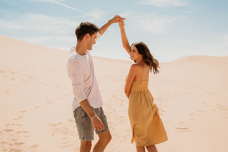 Influencers Jess and Gabriel Conte hold hands and dance together in front of desert landscape