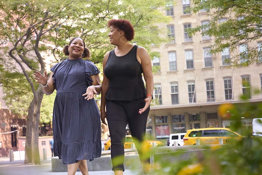 Two sisters in conversation as they walk down the street