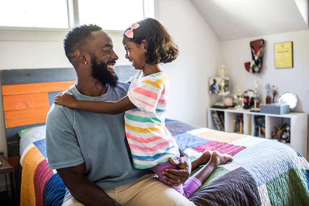 father and daughter laughing in bedroom