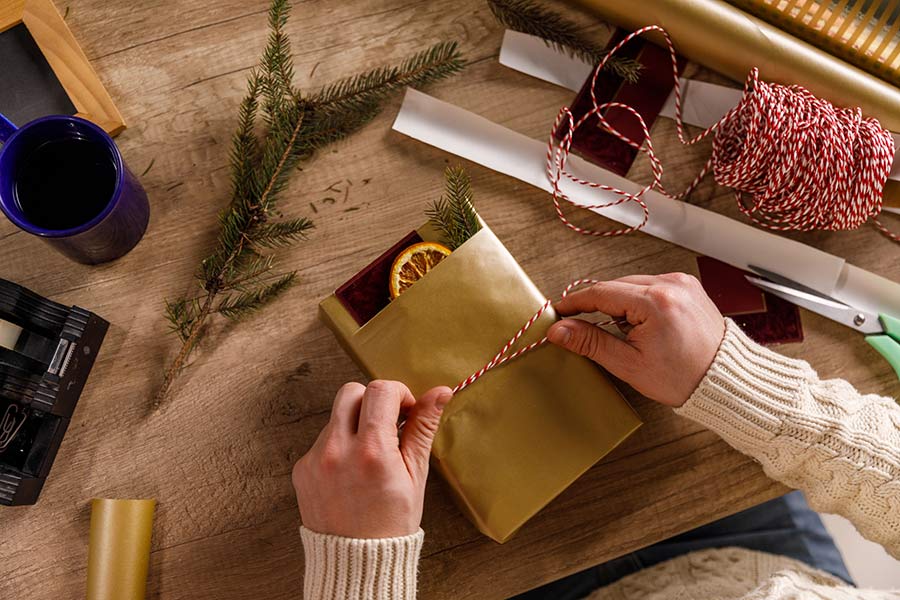 Hands wrap a homemade gift with festive twine