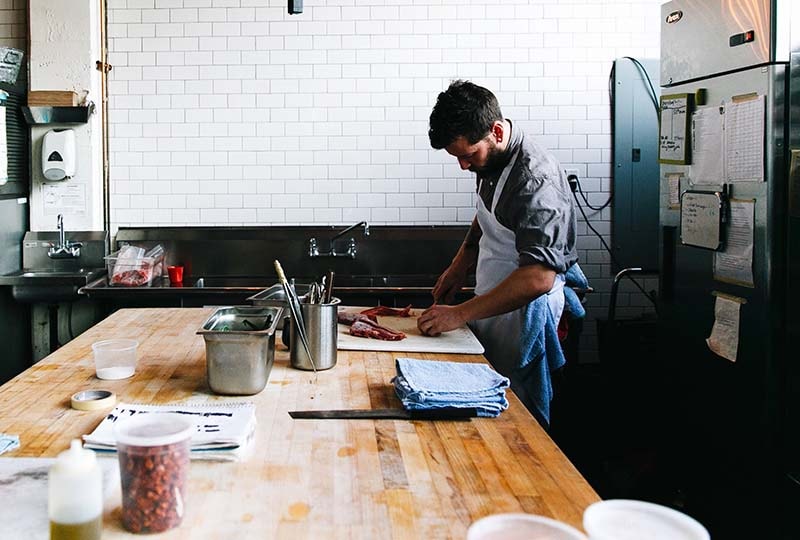 adult man working in kitchen at a wooden table