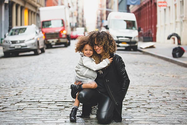 mother and young daughter hugging in the middle of a city street