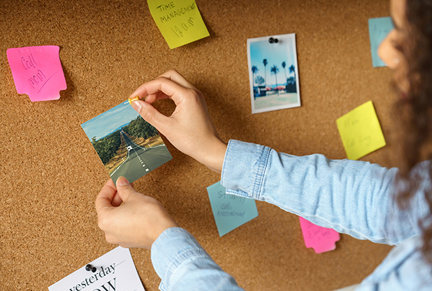 Woman pinning a photo of a rural road on a cork board